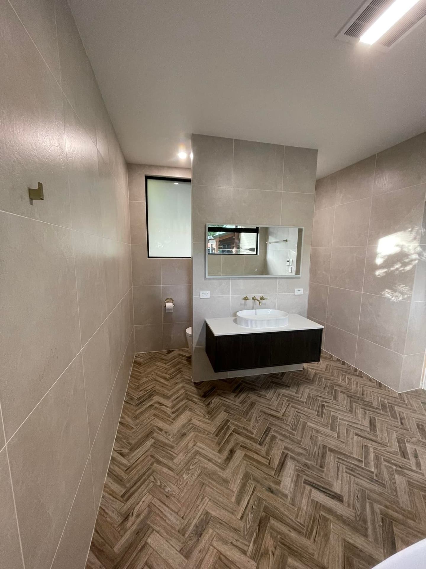 Bathroom tiling project in Adelaide with stone-look walls and herringbone timber floor