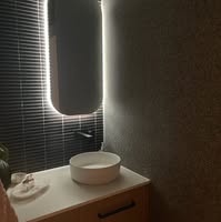 Custom vanity with backlit mirror and textured feature wall tiling